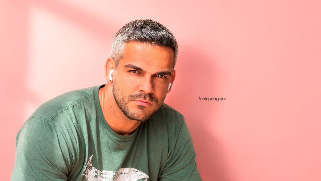 Caique Aguiar com a cabeça um pouco inclinada para a direita e olhando de maneira séria para a frente.