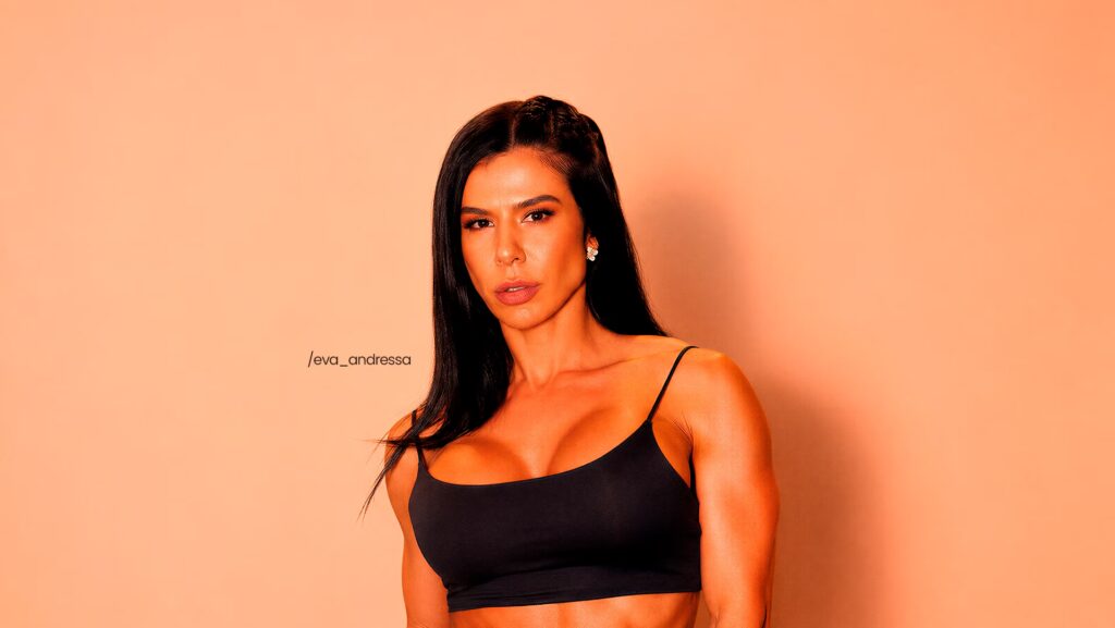 Eva Andressa está com uma blusinha preta. Ela está olhando para a frente.