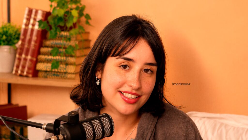 Martina Oliveira de frente enquanto é entrevistada em um podcast.