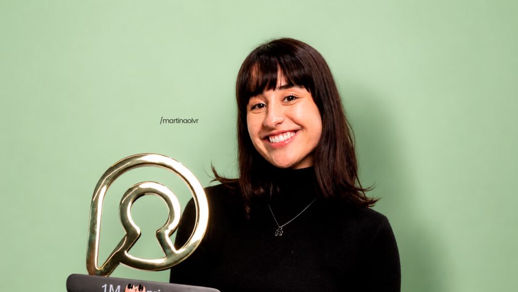 Martina Oliveira feliz olhando pra frente. Ela está segurando seu troféu da Privacy.