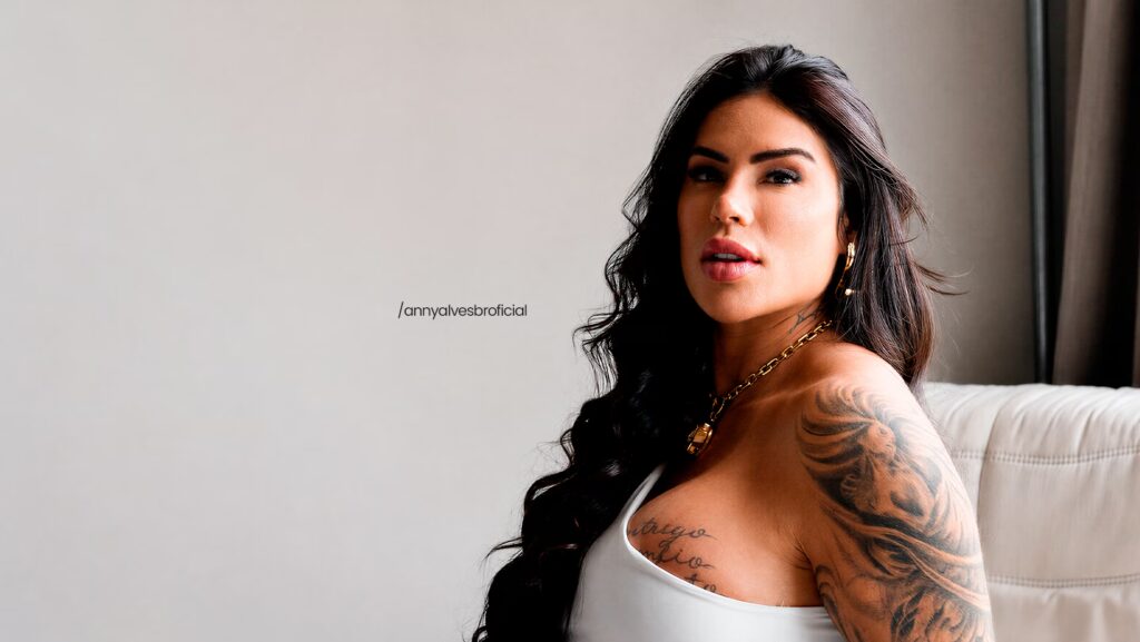 Anny Alves está usando uma blusinha branca e olhando de lado para a foto.