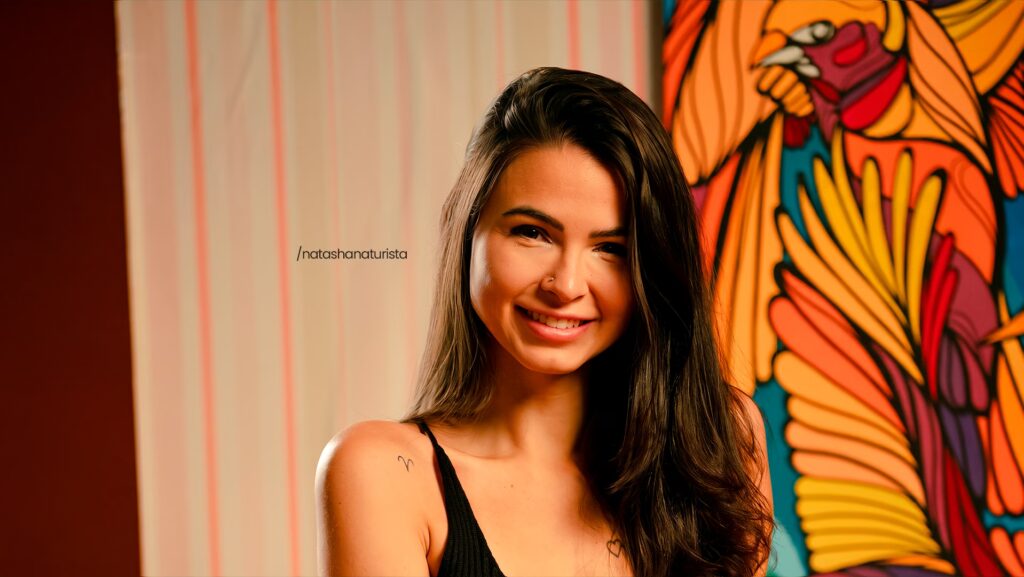 Natasha Naturista sorrindo para a foto.