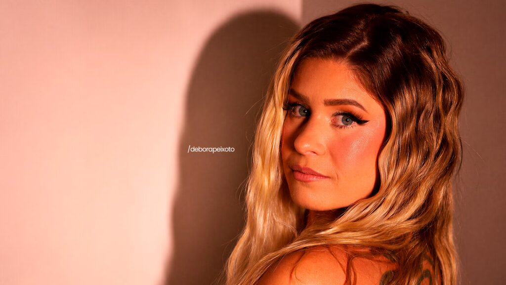 Debora Peixoto posando para a foto virada de costas e olhando para trás.