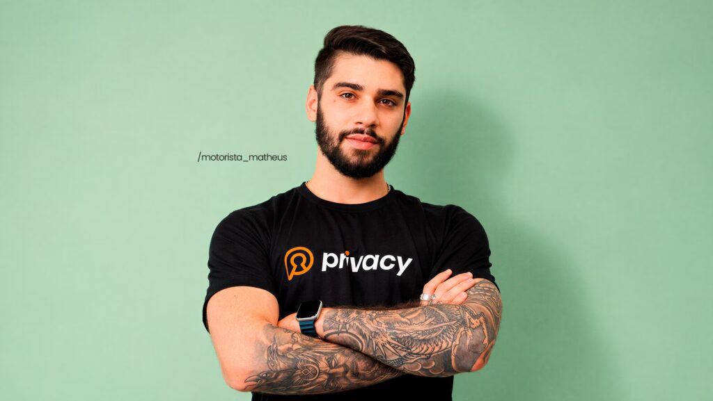 Matheus Motorista com os braços cruzados e utilizando uma camiseta da Privacy