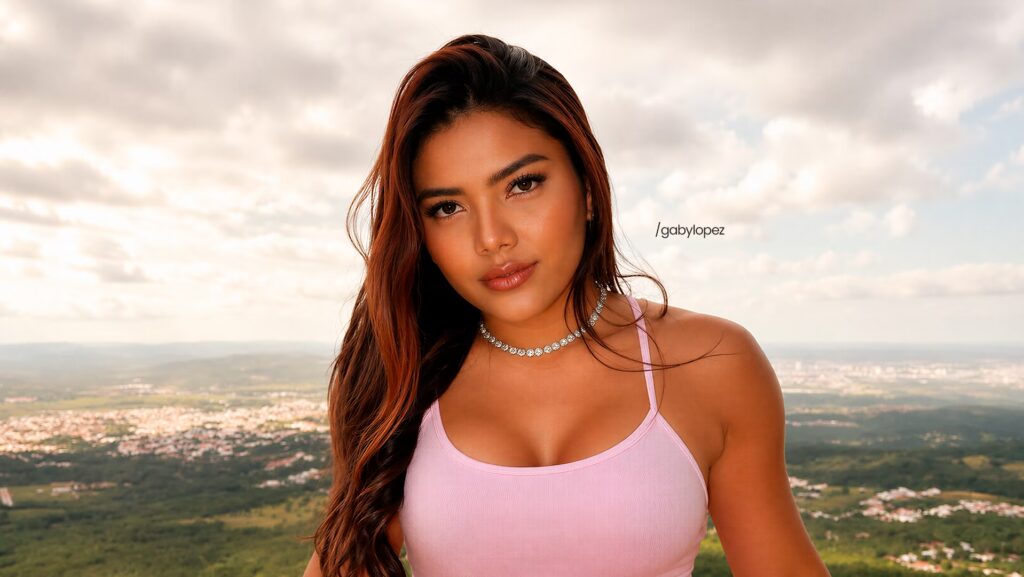 Gaby Lopez olhando séria para a foto. Ela esta vestindo uma blusa rosa.