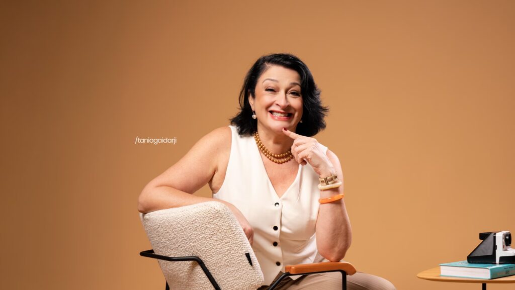 Tânia Gaidarji sentada de lado em poltrona.